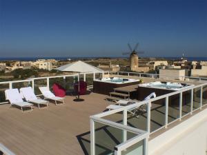 a deck with chairs and a pool and a windmill at GozoWindmill Apartments in Qala