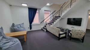 a living room with a tv and a staircase at Kampus Hotel Poruba in Ostrava