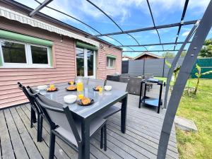 patio ze stołem i krzesłami na pokładzie w obiekcie Cottage Le Rosie au bord du lac avec jacuzzi w mieście Prouilly