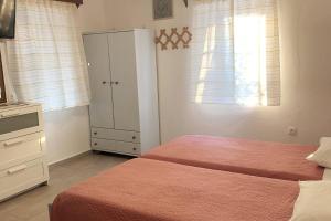 een slaapkamer met 2 bedden, een dressoir en een kast bij Aloe House in Patmos