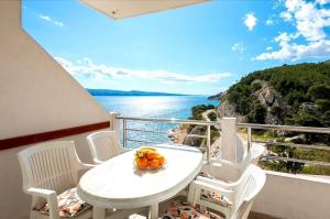 a table and chairs on a balcony with a view of the water at Apartment Complex in Lokva Rogoznica in Lokva Rogoznica