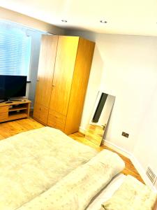 Un dormitorio con una cama y un armario de madera. en Vf apartments kingsbury, en The Hyde