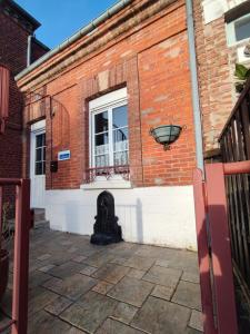 un bâtiment en briques avec une fenêtre et une bouche d'incendie dans l'établissement Tribord, charmante maison en duplex au cœur du Crotoy – Idéale pour un séjour en Baie de Somme, au Crotoy