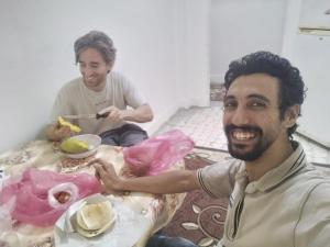two men sitting at a table with a plate of food at Ammar Pyramids View in Cairo