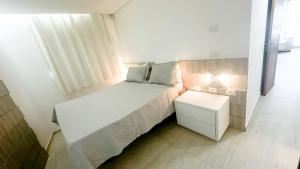 a small bedroom with a white bed and a night stand at Casa e Flat Rio e Praia in Paulista