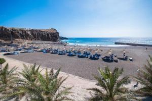 ein Strand mit Stühlen und Sonnenschirmen und das Meer in der Unterkunft Villa Las Vistas Costa Adeje in Callao Salvaje