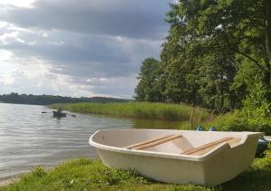 a white boat sitting on the shore of a lake at Domki na Mazurach - Rybical 65 in Ryn