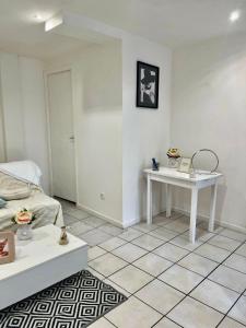 ein weißes Zimmer mit einem Bett und einem Tisch in der Unterkunft Logement accueillant in Gaillon