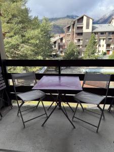 einen lila Tisch und Stühle auf einem Balkon mit Aussicht in der Unterkunft Logement cosy à la montagne in Bourg-Saint-Maurice
