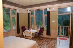 a room with a table and chairs and windows at Perfect Home for Stay in Jibhi