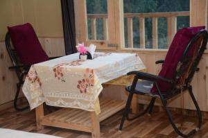 a table and two chairs in a room with a window at Perfect Home for Stay in Jibhi