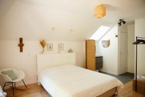 a bedroom with a white bed and a chair at La Borgnardais - chambres étape tout équipées in Loutehel