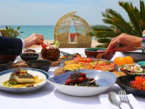 a table with plates of food on the beach at Croisette Beach Hotel Cannes - MGallery Collection in Cannes