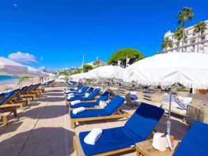 a row of blue lounge chairs on the beach at Croisette Beach Hotel Cannes - MGallery Collection in Cannes
