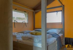 two twin beds in a room with a window at Camping des Gorges de La Loire in Aurec-sur-Loire