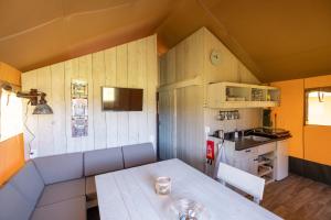 a dining room with a table and a kitchen at Camping des Gorges de La Loire in Aurec-sur-Loire +20 photos