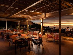 芭东海滩Avista Hideaway Phuket Patong - MGallery的餐厅设有桌椅,享有日落美景。