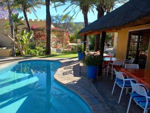 a swimming pool with a table and chairs next to a house at Capbon Guesthouse in Windhoek