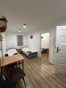 a room with two beds and a desk and a table at Apartamenty Ścinawa in Ścinawa