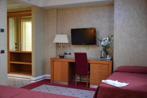 a hotel room with a desk and a tv on a wall at Hotel Perusia in Perugia