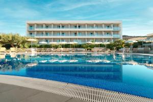 a hotel with a swimming pool in front of a building at Pharos Hvar Bayhill Hotel in Hvar