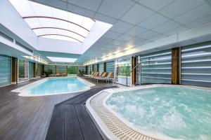une grande piscine intérieure avec un bain à remous dans un bâtiment dans l'établissement Le Relais de La Malmaison, a member of Radisson Individuals, à Rueil-Malmaison