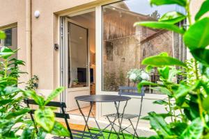 een terras met een tafel en stoelen voor een gebouw bij L’Epicéa - RDJ duplex proche métrohôpital in Oullins