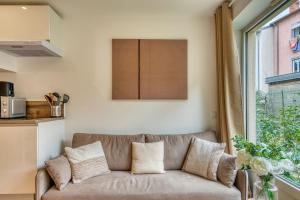 een woonkamer met een bank en een raam bij L’Epicéa - RDJ duplex proche métrohôpital in Oullins