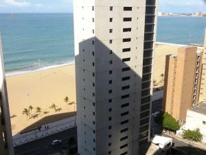 um edifício alto ao lado de uma praia com uma praia em Beach Class em Fortaleza