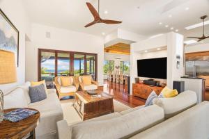 a living room with white furniture and a flat screen tv at Kapiolani Villa home in Princeville