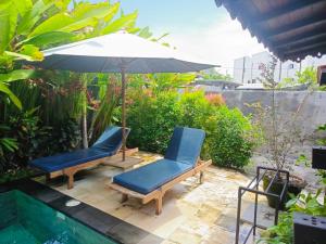 un patio con due sedie e un ombrellone di Villa Ssweta 2 a Canggu