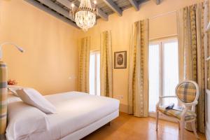 een slaapkamer met een bed, een stoel en een kroonluchter bij Genteel Home Mateos Gago Terrace VI in Sevilla