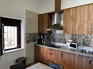 a kitchen with wooden cabinets and a sink and a microwave at Pósito de Don Juan in Fuente Victoria