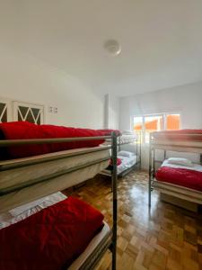 a room with three bunk beds with red sheets at AirPorto Hostel in Maia