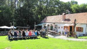 un grupo de personas sentadas en un banco frente a una casa en Gästewohnung Ida, en Oberwart