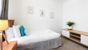 a white bedroom with a bed and a table at Heights Hideaway in Kiama