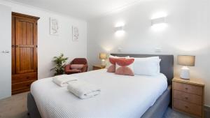 a bedroom with a white bed with towels on it at Heights Hideaway in Kiama