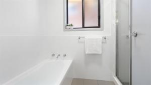 a white bathroom with a sink and a shower at Heights Hideaway in Kiama