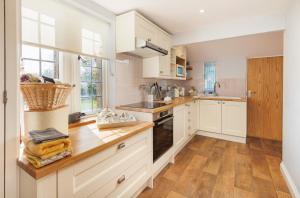 a kitchen with white cabinets and a wooden counter top at The Old Abbey Farmhouse - Stay at Quarr Abbey Monastery - Pet-Friendly Farmhouse with History & Countryside Views, surrounded by woodland & nature in Ryde