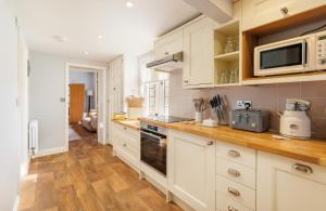 Una cocina con gabinetes blancos y encimera. en The Old Abbey Farmhouse - Stay at Quarr Abbey Monastery - Pet-Friendly Farmhouse with History & Countryside Views, surrounded by woodland & nature, en Ryde