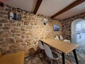 ein Esszimmer mit Steinwänden, einem Holztisch und Stühlen in der Unterkunft Mala kuća od soli pokraj mora 4 osobe Jezera Murter in Jezera