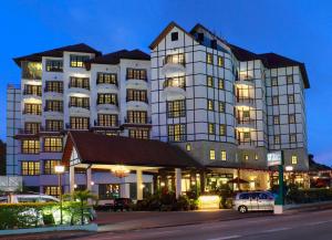 a large white building with cars parked in front of it at Hotel De' La Ferns, Cameron Highlands in Cameron Highlands