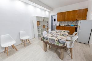 a dining room with a table and white chairs at Borghetto Nora 5 in Gravina di Catania