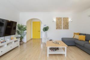 ein Wohnzimmer mit einem blauen Sofa und einer gelben Tür in der Unterkunft Hopstays Vilamoura Aldeia do Golfe - House C3 in Estibeira