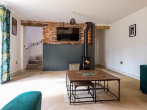 a living room with a table and a fireplace at Threshers Barn in Oswestry