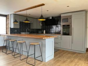 a kitchen with a island with bar stools in it at The Nursery in Crick