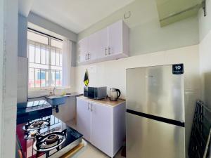 a kitchen with white cabinets and a stainless steel refrigerator at Kampala city center vin haven in Kampala
