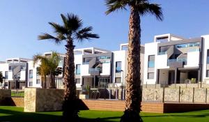 two palm trees in front of a white building at Punta Prima & Oasis Beach apartment in Punta Prima