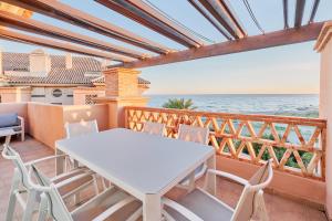 Una mesa blanca y sillas en un balcón con vista al mar. en Beautiful Penthouse, en Torrox Costa