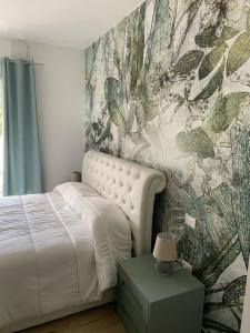 a bedroom with a white bed and a wall mural at Cassino - Appartamento Green - Parco del Gari in Cassino
